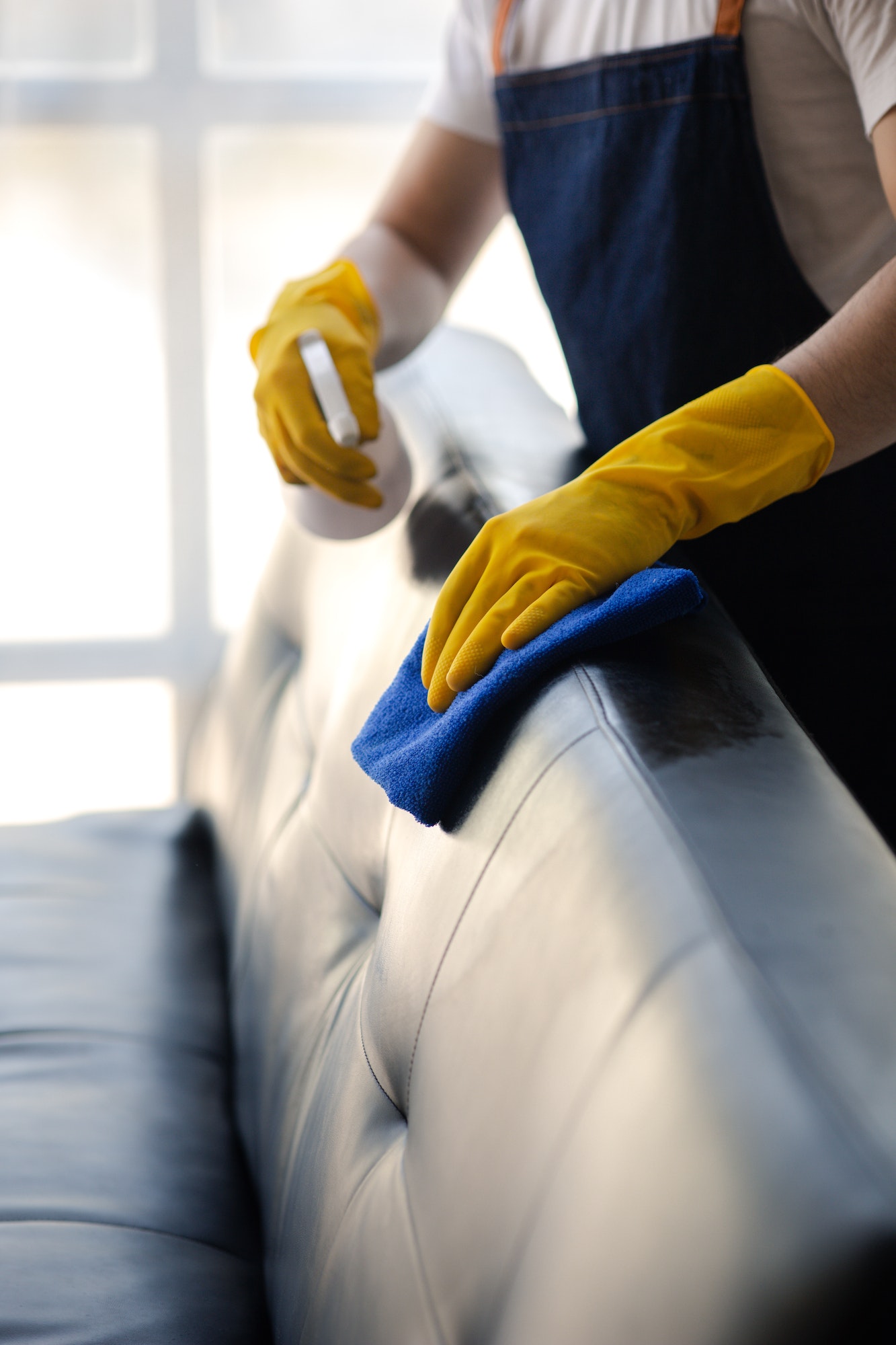 Person cleaning the room, cleaning staff is using cloth and spraying disinfectant.